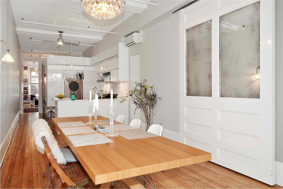 Photo of a mid-sized modern dining room in New York with white walls, medium hardwood floors, no fireplace and brown floor.