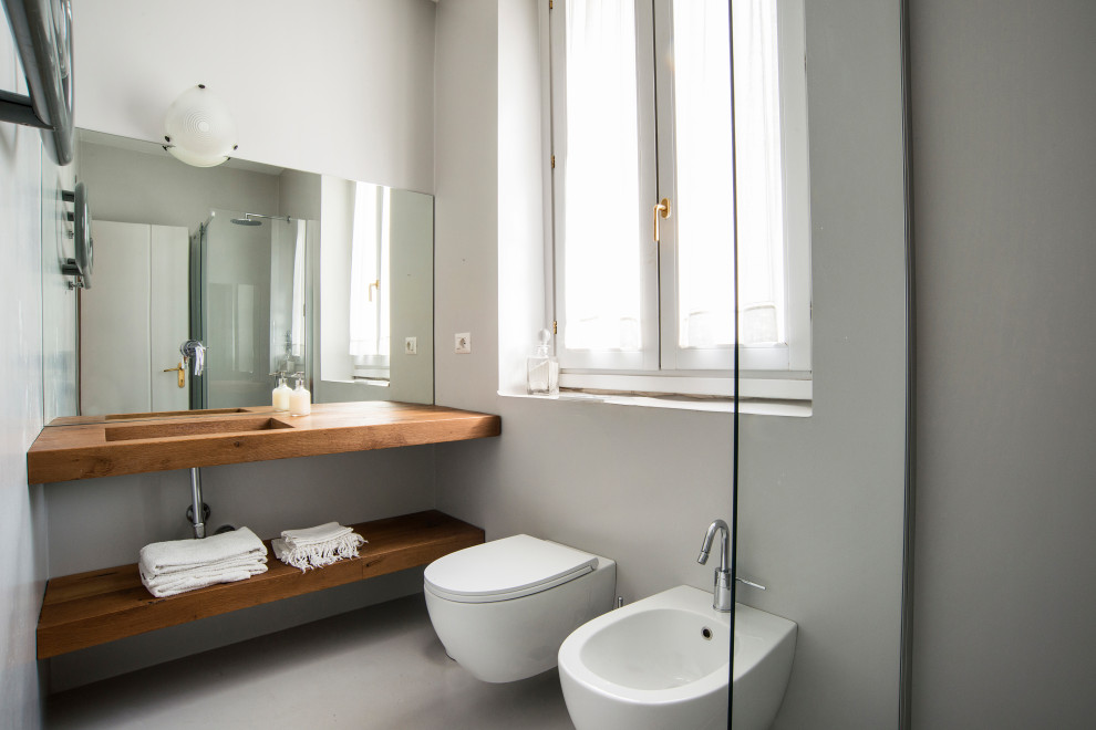 Источник вдохновения для домашнего уюта: туалет среднего размера в современном стиле с раздельным унитазом, серыми стенами, врезной раковиной, столешницей из дерева, серым полом и коричневой столешницей