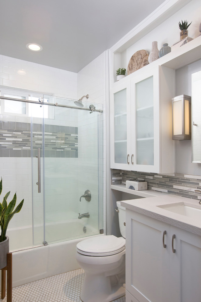 This is an example of a mid-sized contemporary kids bathroom in Denver with shaker cabinets, white cabinets, an alcove tub, a shower/bathtub combo, white tile, gray tile, grey walls, an undermount sink, engineered quartz benchtops, white floor, a sliding shower screen, a two-piece toilet, matchstick tile and mosaic tile floors.