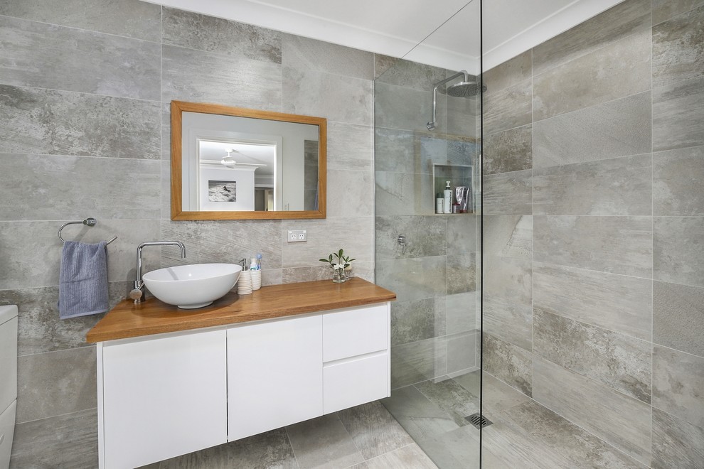This is an example of a contemporary bathroom in Sydney with flat-panel cabinets, white cabinets, a curbless shower, a two-piece toilet, gray tile, grey walls, a vessel sink and an open shower.