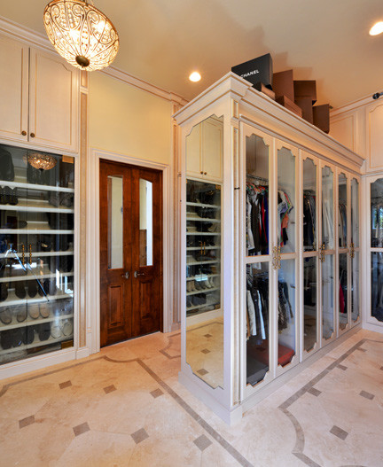 Large traditional gender-neutral walk-in wardrobe in Dallas with glass-front cabinets and beige cabinets.