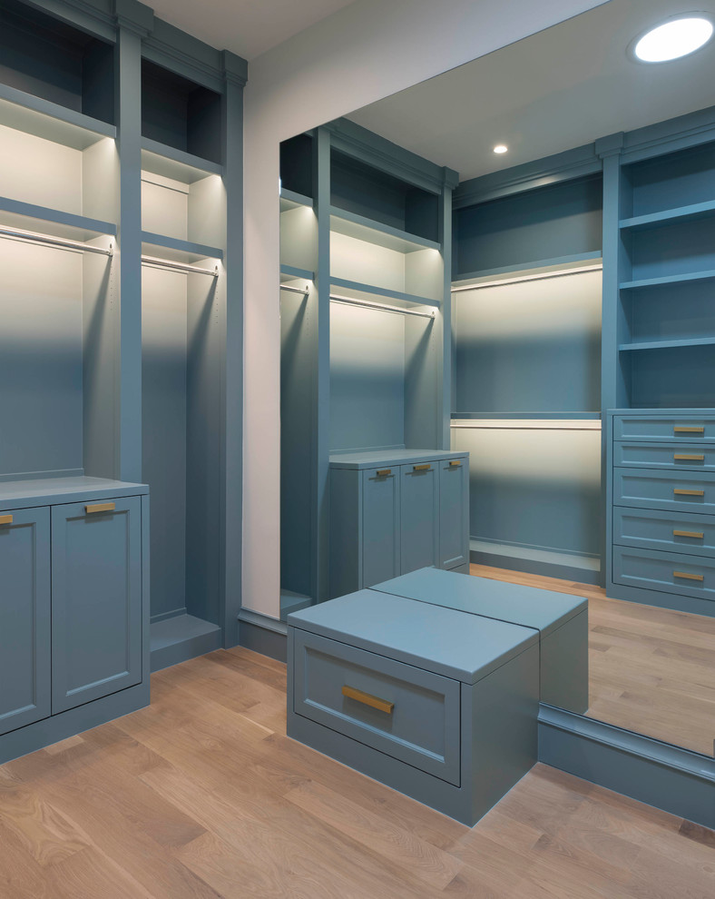 This is an example of a mediterranean men's walk-in wardrobe in Dallas with shaker cabinets, blue cabinets and light hardwood floors.