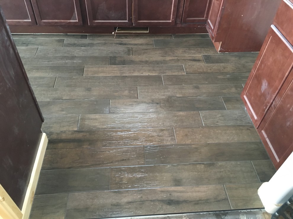 Example of a large mountain style l-shaped porcelain tile eat-in kitchen design with flat-panel cabinets, dark wood cabinets and an island