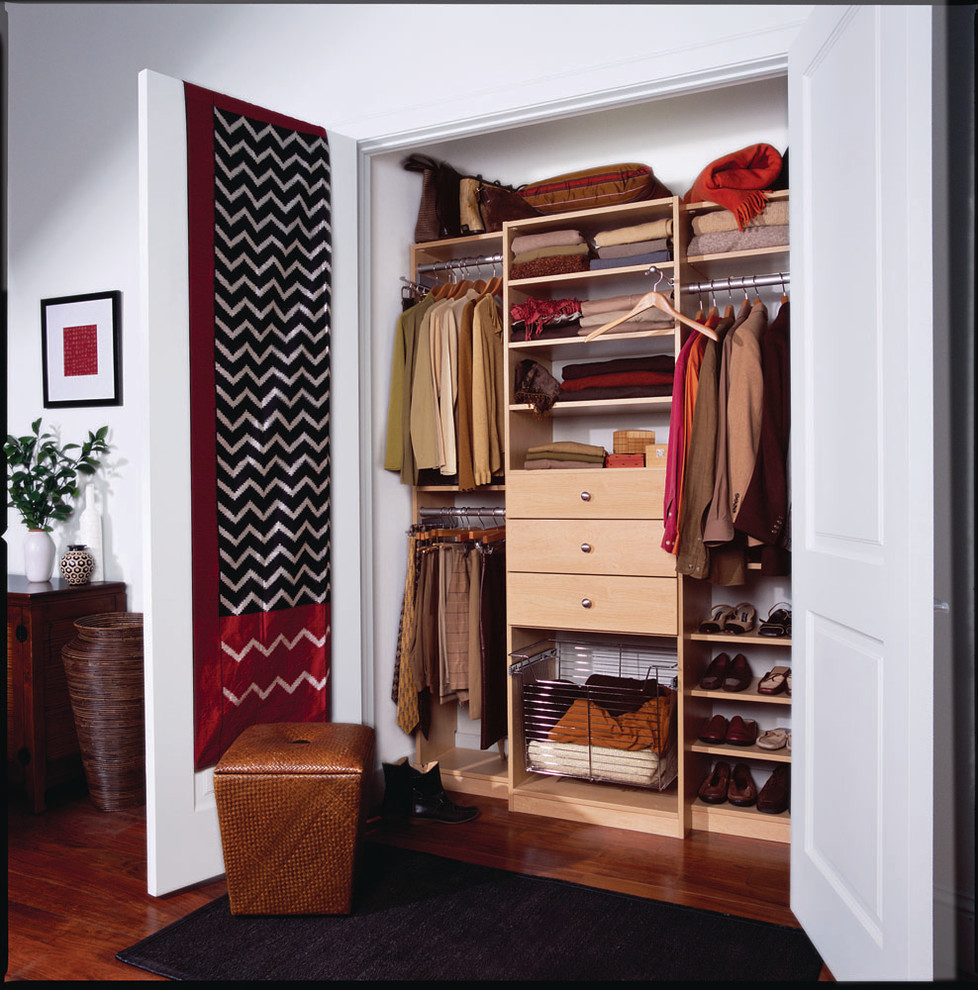 Design ideas for a mid-sized traditional gender-neutral built-in wardrobe in New York with dark hardwood floors, light wood cabinets and flat-panel cabinets.