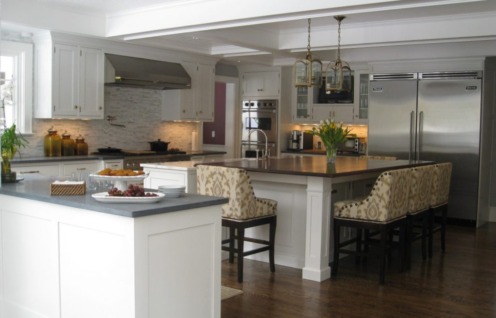 This is an example of a large traditional u-shaped separate kitchen in New York with a farmhouse sink, shaker cabinets, white cabinets, concrete benchtops, beige splashback, matchstick tile splashback, stainless steel appliances, dark hardwood floors, with island, brown floor and grey benchtop.