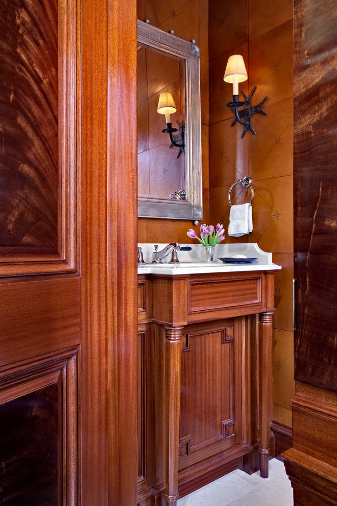 Inspiration for a small traditional powder room in New York with an undermount sink, furniture-like cabinets, medium wood cabinets, marble benchtops, a two-piece toilet, white tile, stone tile, brown walls, limestone floors and white benchtops.