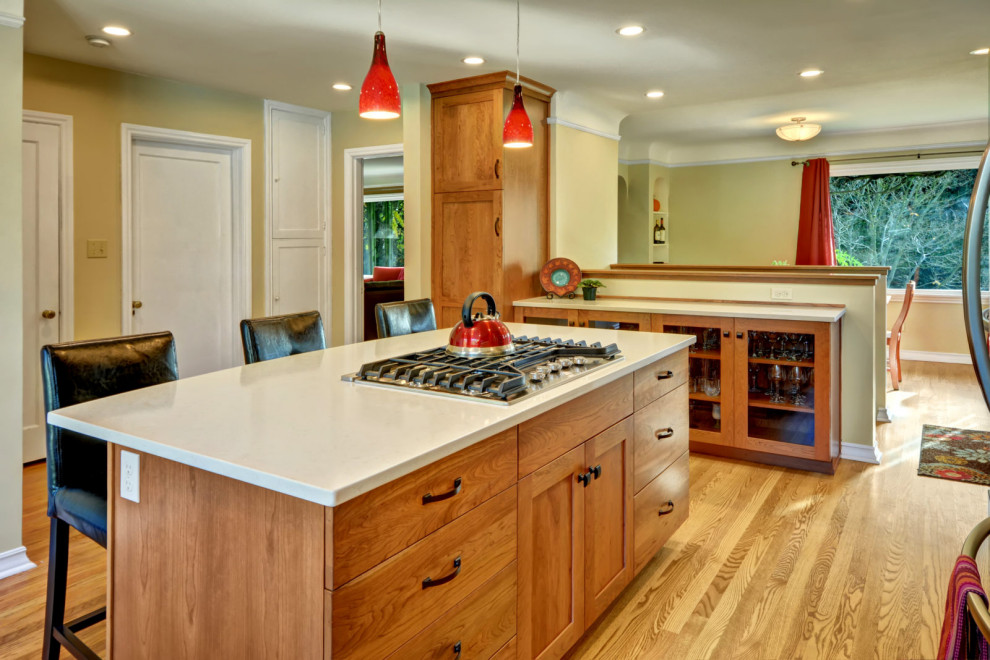 Example of a l-shaped medium tone wood floor and brown floor eat-in kitchen design in Seattle with an undermount sink, shaker cabinets, medium tone wood cabinets, red backsplash, mosaic tile backsplash, stainless steel appliances, an island and white countertops
