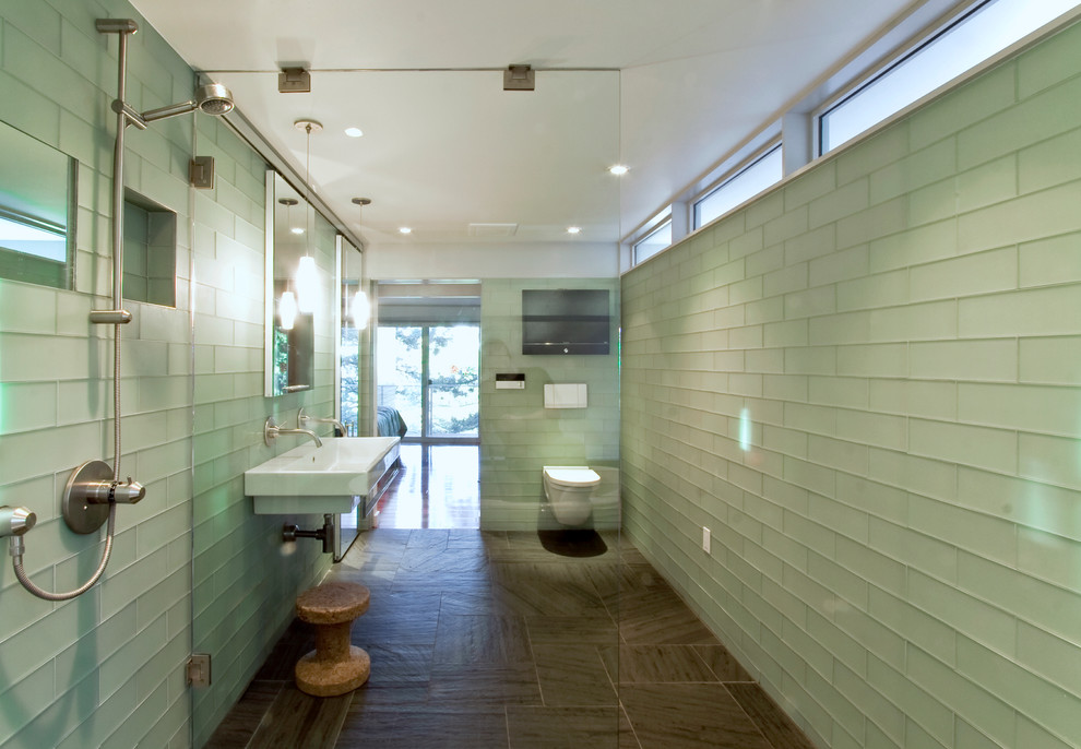 Photo of a contemporary bathroom in New York with an alcove shower, a wall-mount toilet, green tile, glass tile and a vessel sink.