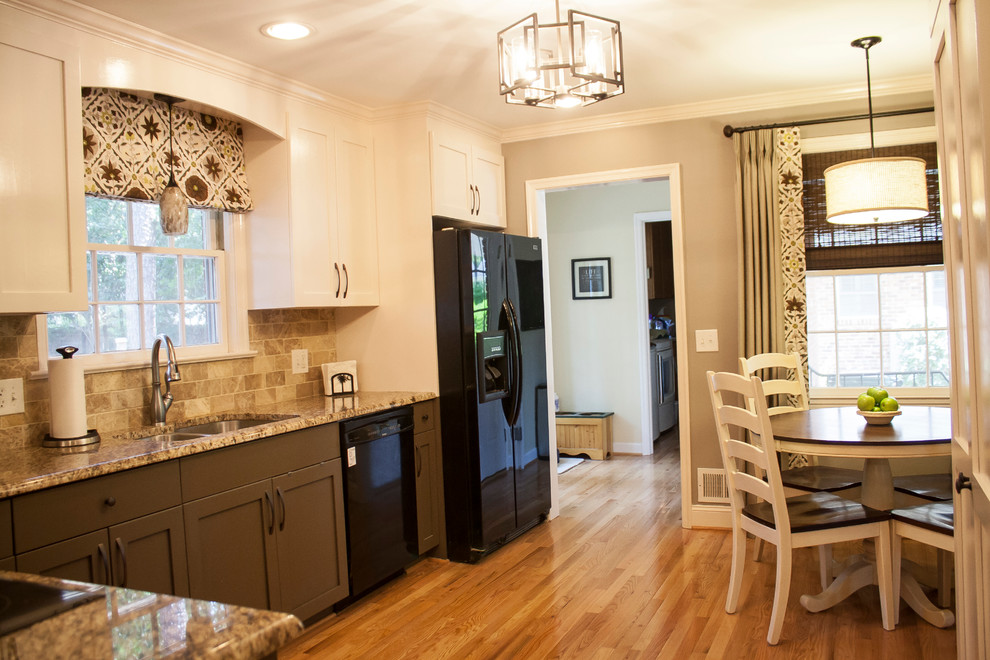 Example of a mid-sized transitional l-shaped light wood floor eat-in kitchen design with a double-bowl sink, shaker cabinets, brown cabinets, granite countertops, beige backsplash, porcelain backsplash, black appliances and no island