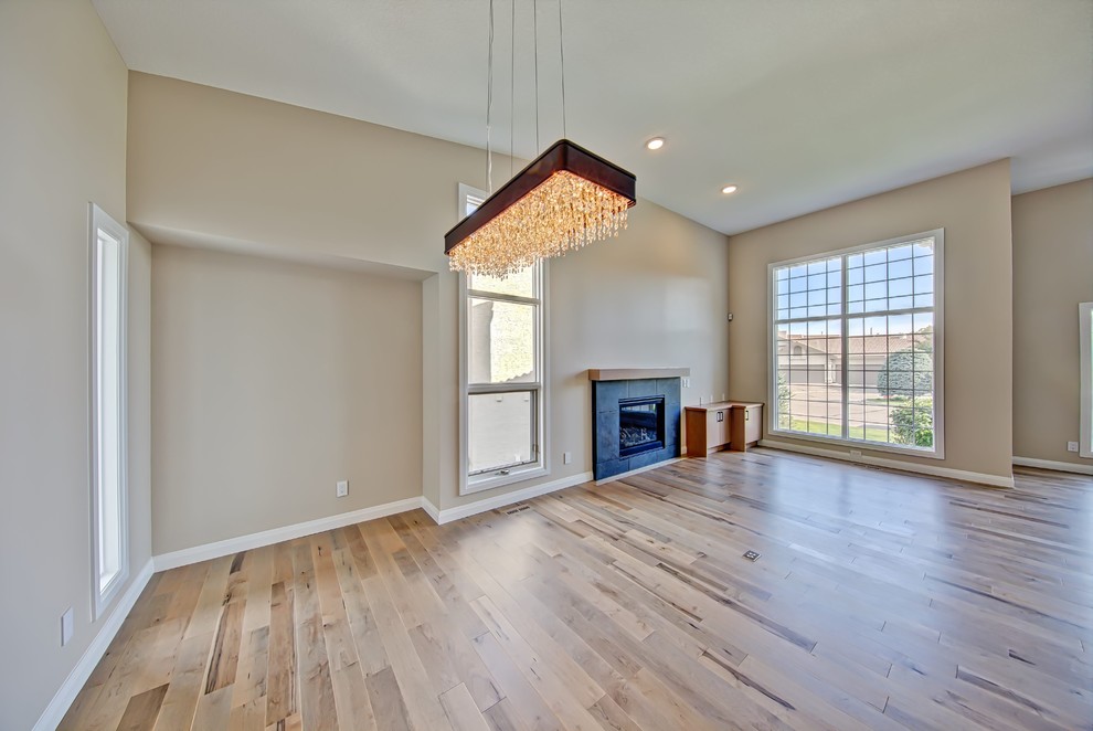 Photo of a modern family room in Calgary with beige walls, light hardwood floors, a standard fireplace and a tile fireplace surround.