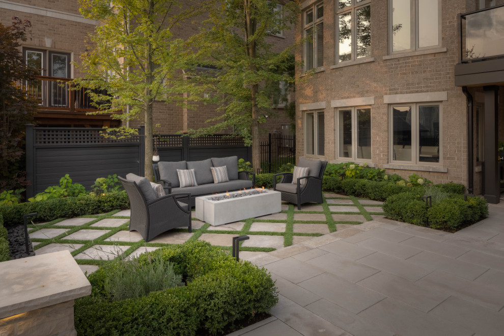 This is an example of a medium sized contemporary back patio in Toronto with a fire feature, brick paving and no cover.