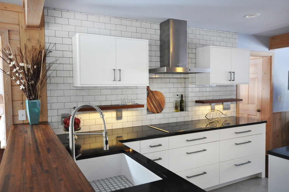 Inspiration for a mid-sized transitional l-shaped dark wood floor eat-in kitchen remodel in Grand Rapids with an undermount sink, flat-panel cabinets, white cabinets, soapstone countertops, white backsplash, subway tile backsplash, stainless steel appliances and an island