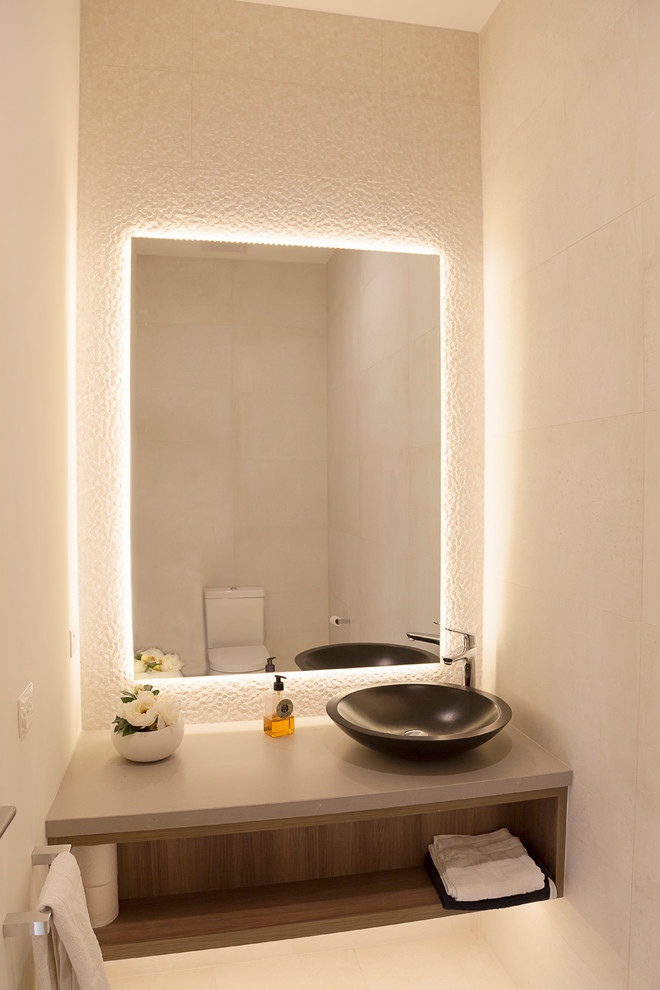 Design ideas for a mid-sized contemporary powder room in Melbourne with open cabinets, brown cabinets, a wall-mount toilet, white tile, porcelain tile, white walls, porcelain floors, a vessel sink, engineered quartz benchtops and beige floor.