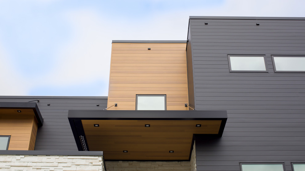 Photo of a large modern three-storey grey house exterior in Grand Rapids with metal siding.