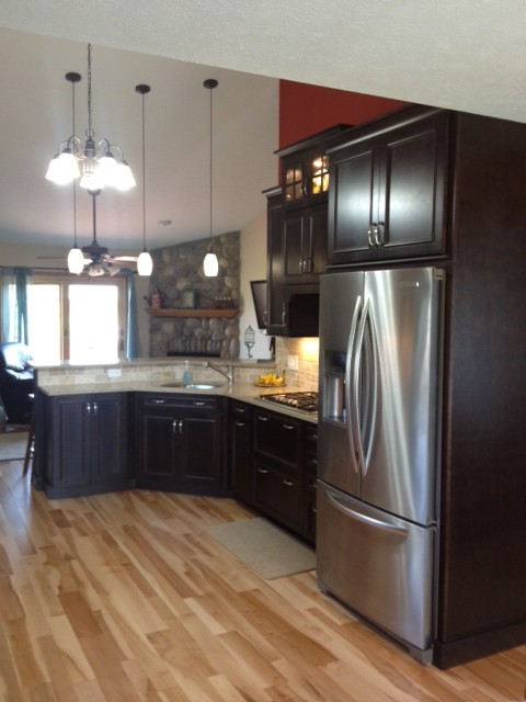 Example of a large transitional galley light wood floor kitchen pantry design with an undermount sink, dark wood cabinets, quartz countertops, gray backsplash, stone tile backsplash and stainless steel appliances