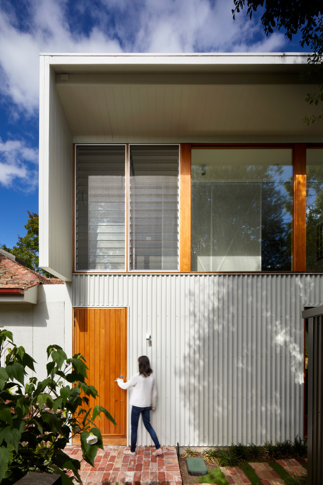 Modelo de fachada de casa blanca y blanca contemporánea de tamaño medio de dos plantas con revestimiento de metal, tejado plano y tejado de metal