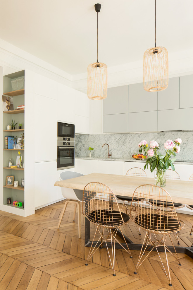 Photo of a large transitional single-wall open plan kitchen in Paris with an undermount sink, marble benchtops, multi-coloured splashback, marble splashback, stainless steel appliances, medium hardwood floors, no island, brown floor and flat-panel cabinets.