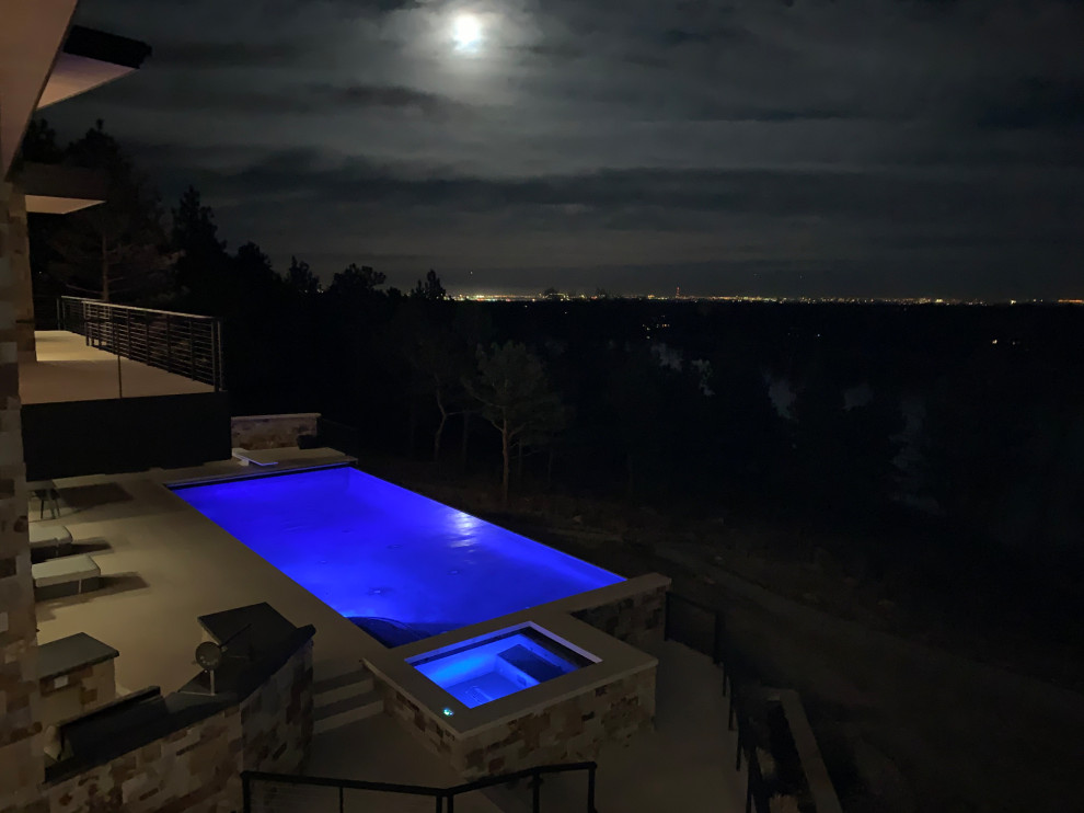 Hot tub - mid-sized backyard rectangular infinity hot tub idea in Denver