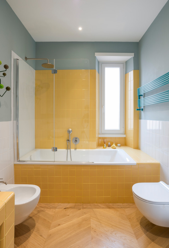 Пример оригинального дизайна: ванная комната в современном стиле с ванной в нише, желтой плиткой, синими стенами, паркетным полом среднего тона и коричневым полом