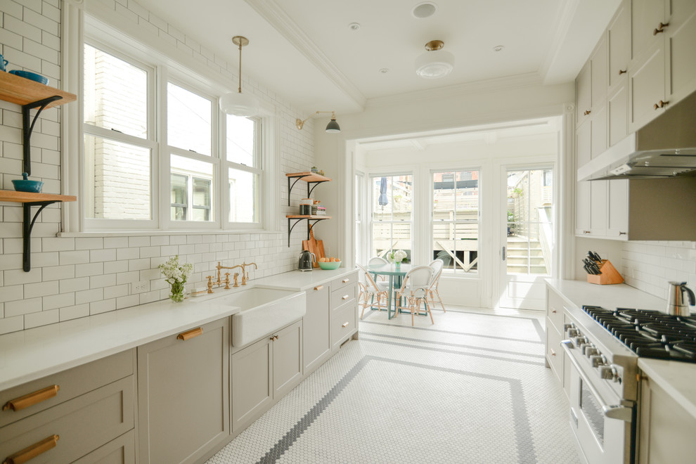This is an example of a mid-sized traditional galley eat-in kitchen in DC Metro with a farmhouse sink, recessed-panel cabinets, beige cabinets, quartz benchtops, white splashback, subway tile splashback, stainless steel appliances, porcelain floors, no island, white floor and white benchtop.