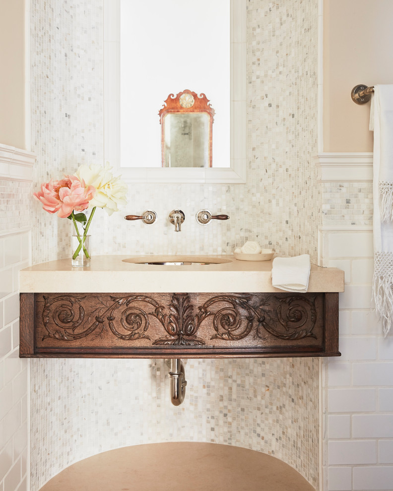 Small mediterranean powder room in Los Angeles with open cabinets, distressed cabinets, a one-piece toilet, white tile, mosaic tile, beige walls, dark hardwood floors, an undermount sink, limestone benchtops, brown floor and beige benchtops.