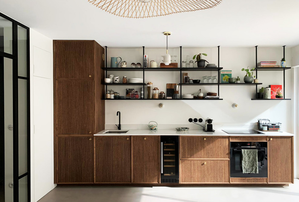 Inspiration for a small contemporary single-wall open plan kitchen in Paris with an integrated sink, beaded inset cabinets, dark wood cabinets, quartz benchtops, white splashback, engineered quartz splashback, black appliances, concrete floors, grey floor and white benchtop.