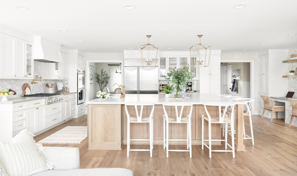 Photo of a large scandinavian u-shaped eat-in kitchen in San Francisco with a farmhouse sink, recessed-panel cabinets, white cabinets, quartzite benchtops, white splashback, marble splashback, stainless steel appliances, light hardwood floors, with island, beige floor and white benchtop.