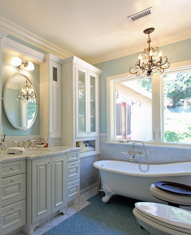 Bild på ett mellanstort vintage vit vitt en-suite badrum, med luckor med upphöjd panel, vita skåp, ett badkar med tassar, en hörndusch, vit kakel, marmorkakel, blå väggar, klinkergolv i keramik, ett undermonterad handfat, marmorbänkskiva, blått golv och dusch med gångjärnsdörr