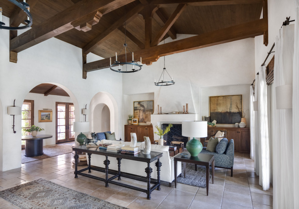 Inspiration for a large mediterranean formal open concept living room in Orange County with white walls, travertine floors, a standard fireplace, a plaster fireplace surround, no tv and beige floor.