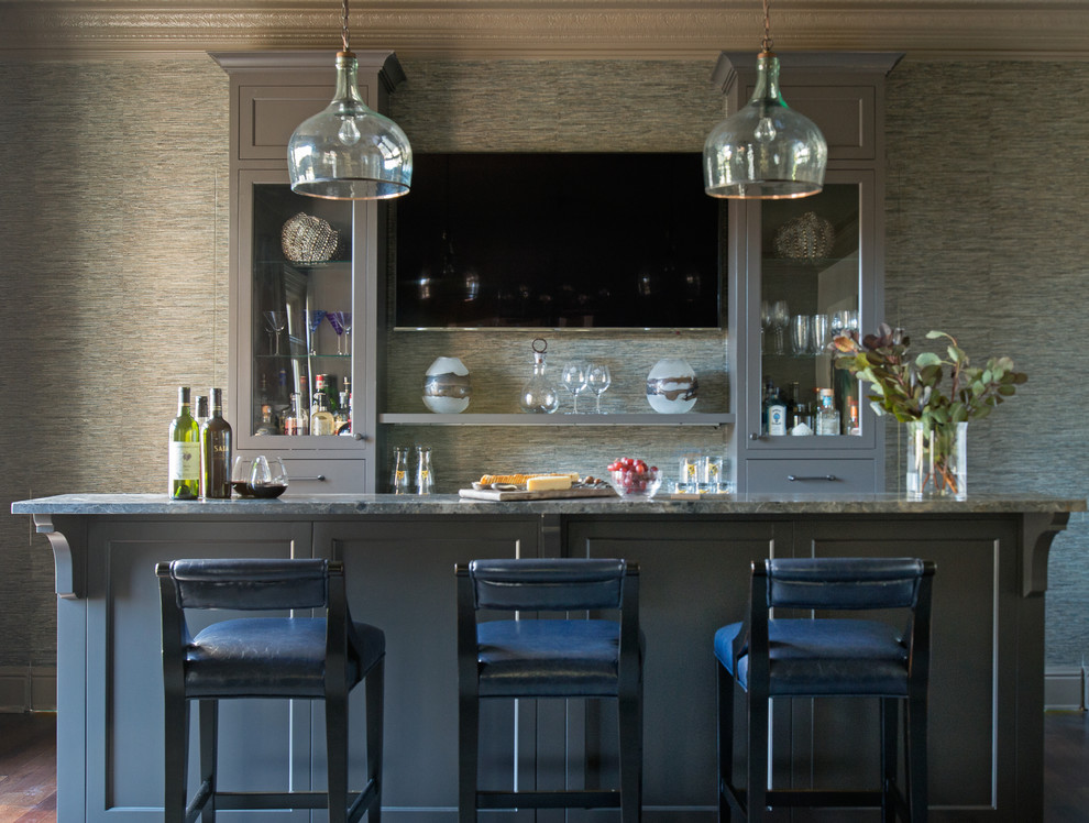 Photo of a transitional galley seated home bar in New York with glass-front cabinets, brown cabinets, granite benchtops and multi-coloured benchtop.