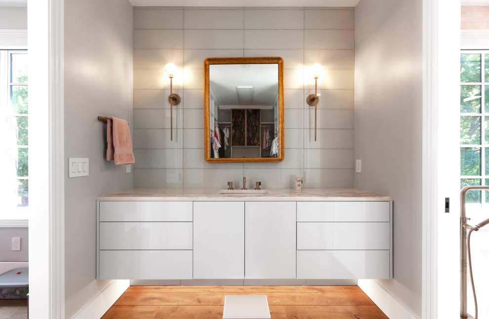 Example of a mid-sized minimalist kids' pink tile and glass tile porcelain tile, white floor and single-sink bathroom design in Indianapolis with flat-panel cabinets, white cabinets, a wall-mount toilet, pink walls, an undermount sink, quartz countertops, a hinged shower door, beige countertops and a floating vanity