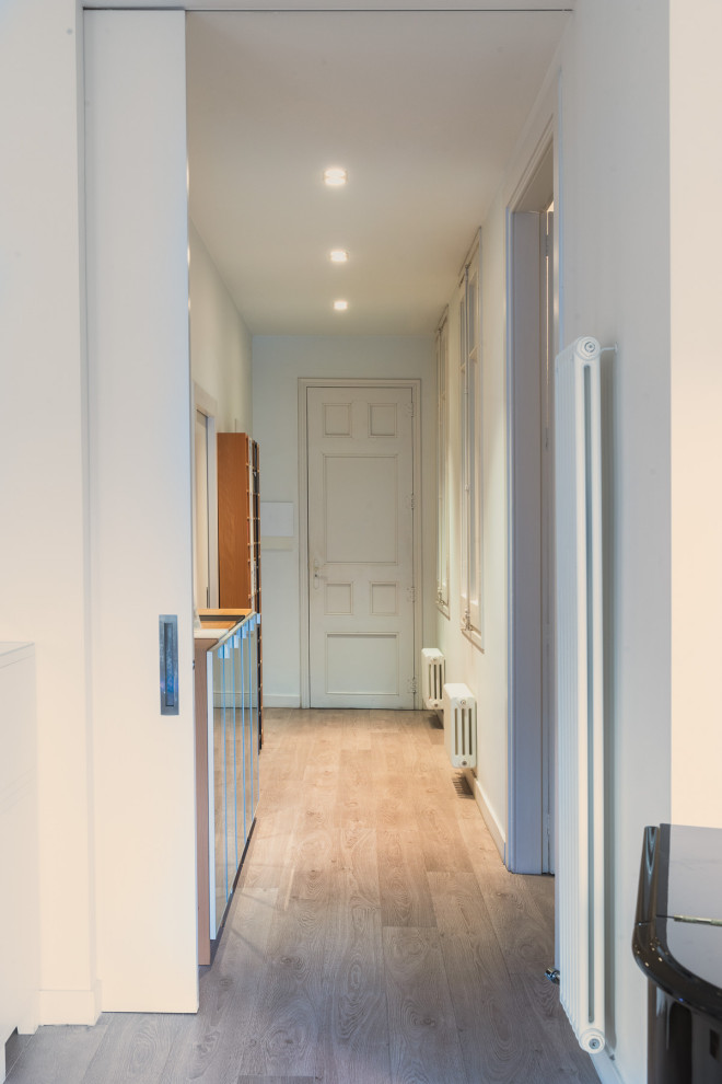 Foto de recibidores y pasillos actuales de tamaño medio con paredes blancas, suelo de madera en tonos medios y suelo beige