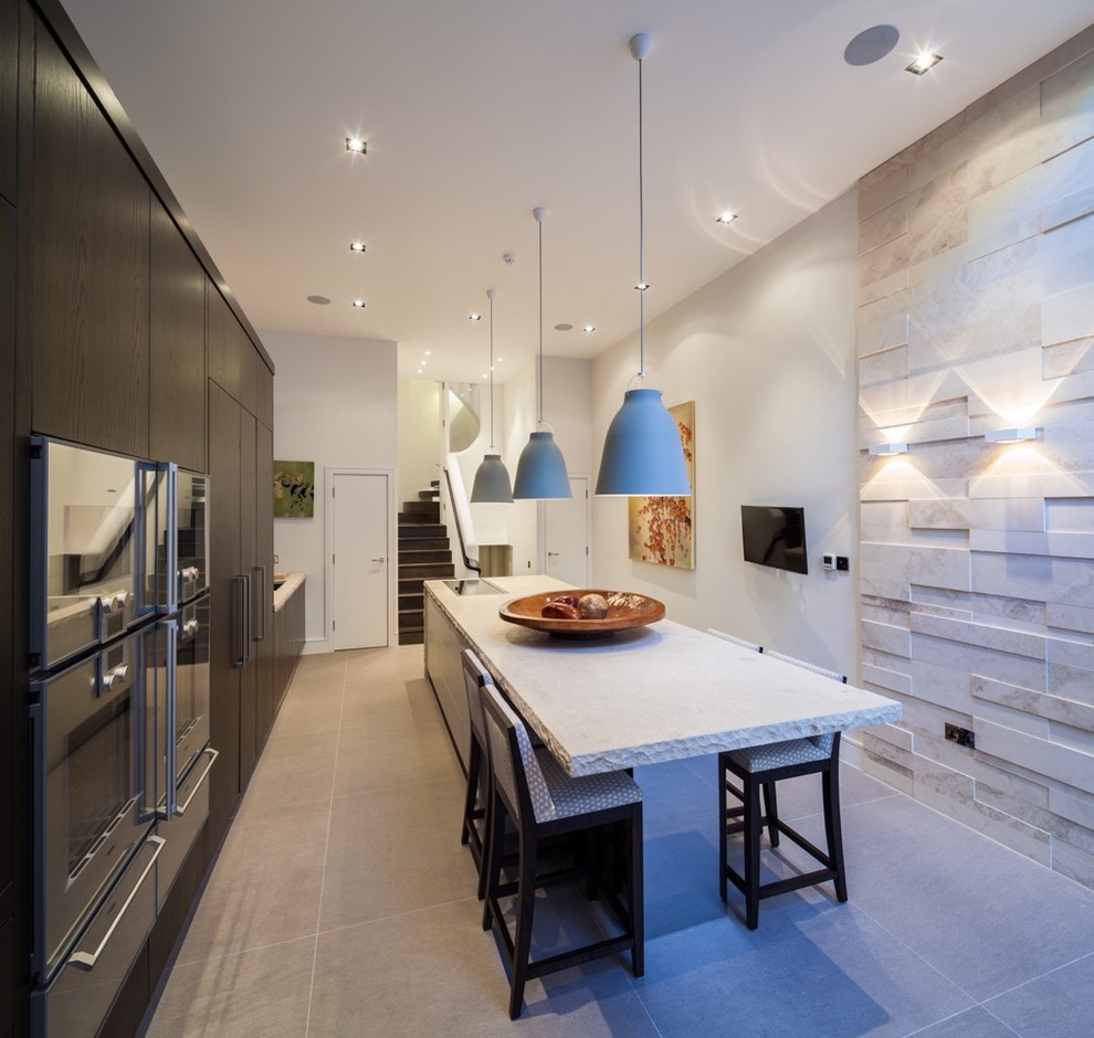 Photo of a large contemporary eat-in kitchen in London with an integrated sink, dark wood cabinets, limestone benchtops, white splashback, glass sheet splashback, stainless steel appliances and with island.
