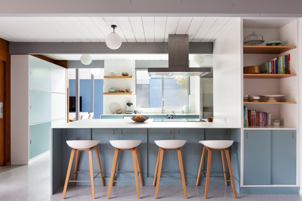 Diseño de cocina retro con armarios con paneles lisos, puertas de armario azules, península, suelo gris, encimeras blancas, machihembrado y vigas vistas