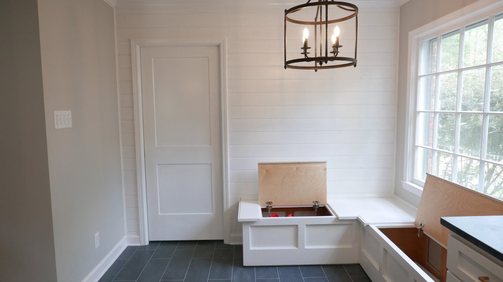 Eat-in kitchen - mid-sized transitional galley porcelain tile and black floor eat-in kitchen idea with a farmhouse sink, shaker cabinets, white cabinets, soapstone countertops, white backsplash, subway tile backsplash, white appliances, an island and black countertops