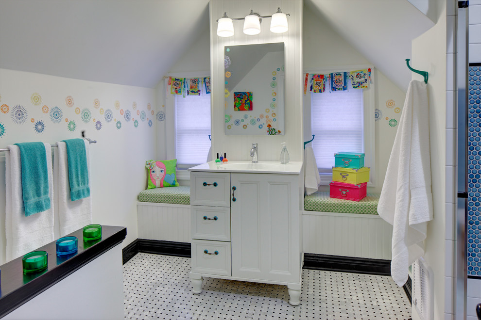 This is an example of a mid-sized eclectic kids bathroom in New York with an integrated sink, furniture-like cabinets, white cabinets, a double shower, a two-piece toilet, multi-coloured tile, ceramic tile, white walls and mosaic tile floors.