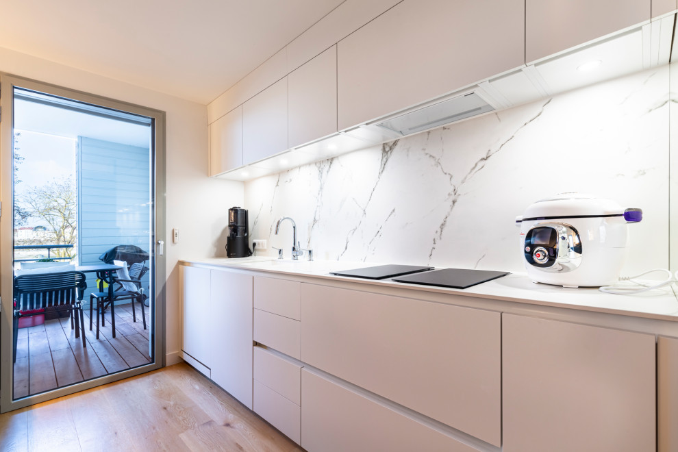Idee per una cucina parallela contemporanea chiusa con paraspruzzi bianco, pavimento in legno massello medio e top nero
