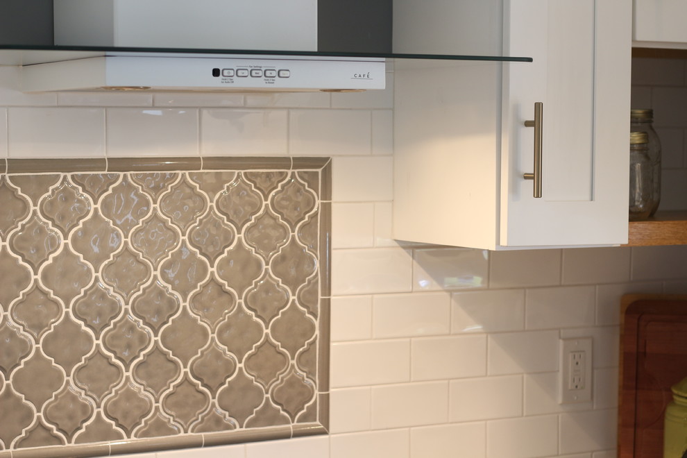 Example of a mid-sized transitional u-shaped medium tone wood floor and brown floor enclosed kitchen design with a farmhouse sink, shaker cabinets, white cabinets, quartz countertops, white backsplash, subway tile backsplash, white appliances, no island and beige countertops