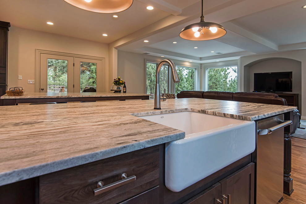 Inspiration for a large transitional l-shaped medium tone wood floor and brown floor open concept kitchen remodel with a farmhouse sink, shaker cabinets, dark wood cabinets, granite countertops, gray backsplash, subway tile backsplash, paneled appliances and an island