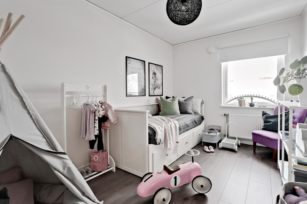 This is an example of a mid-sized scandinavian kids' bedroom for kids 4-10 years old and girls in Gothenburg with white walls, laminate floors and brown floor.