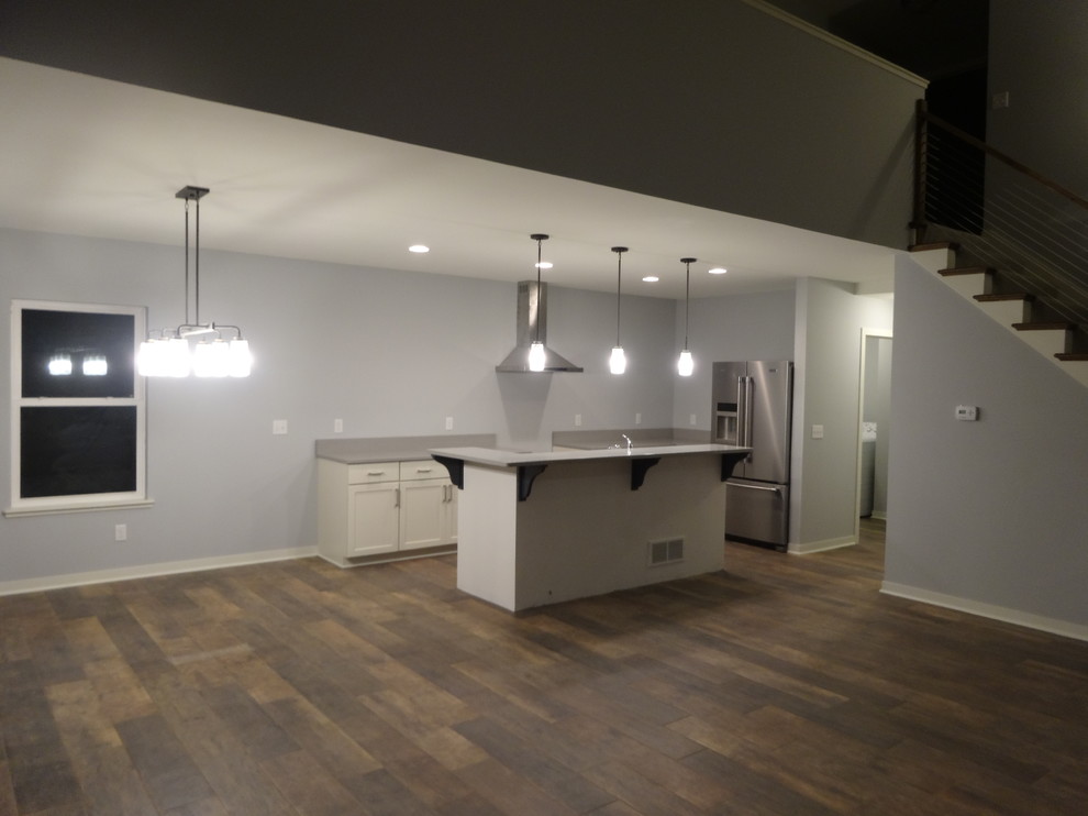 Mid-sized transitional l-shaped porcelain tile eat-in kitchen photo in Milwaukee with a single-bowl sink, recessed-panel cabinets, white cabinets, quartz countertops, gray backsplash, stone slab backsplash, stainless steel appliances and an island