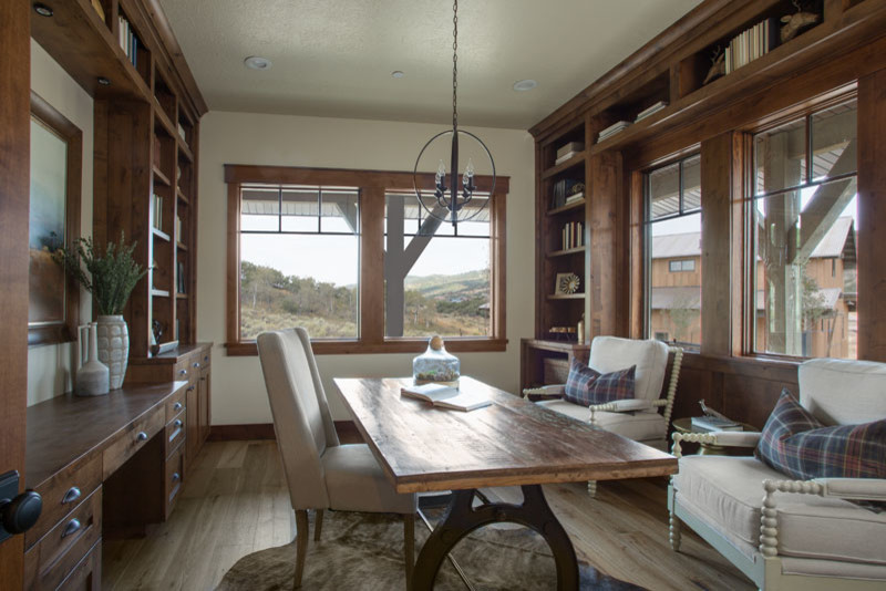 Photo of a large country home office in Salt Lake City with a library, beige walls, light hardwood floors, no fireplace and a freestanding desk.