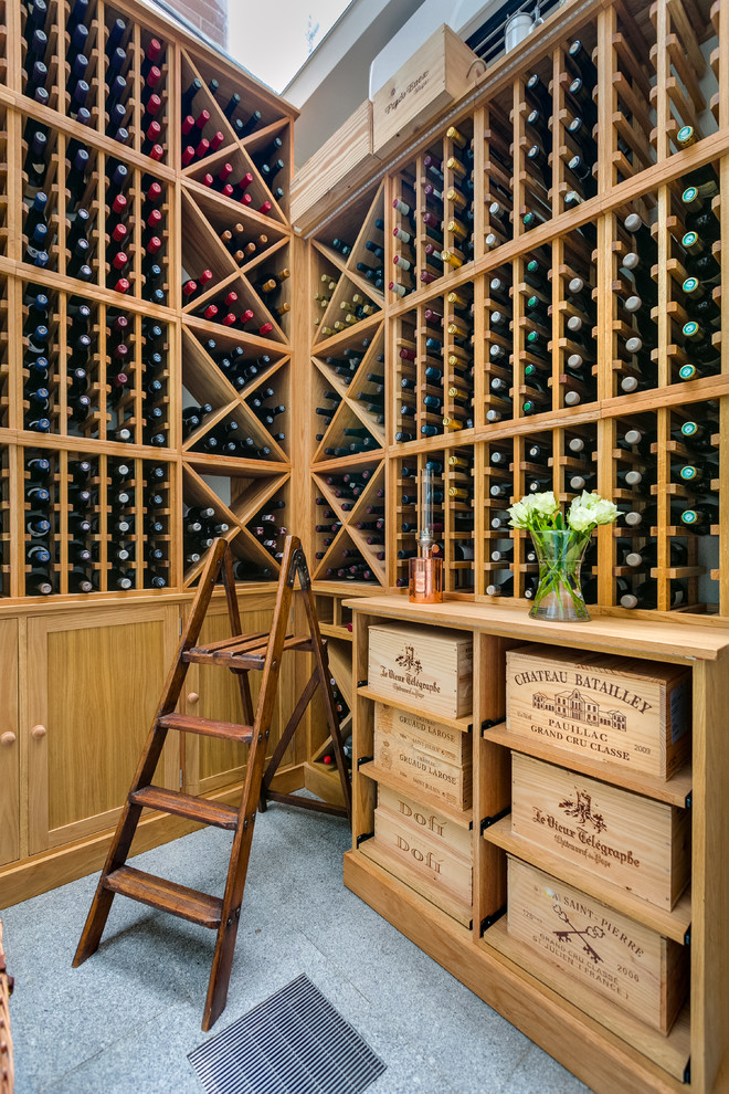 Inspiration for a mid-sized modern wine cellar in London with storage racks and grey floor.