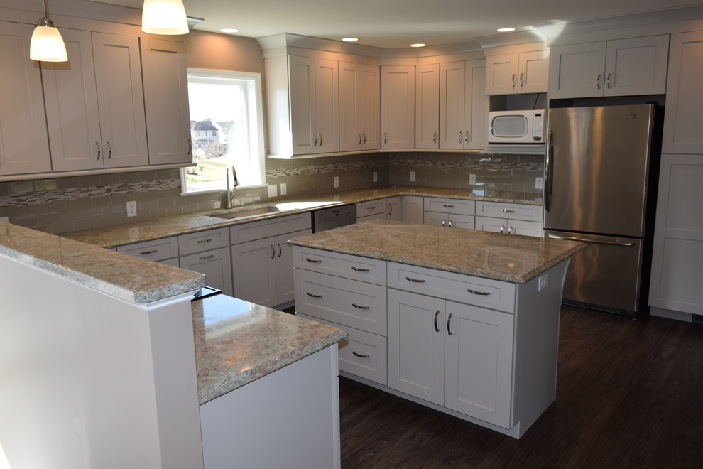 Kitchen - transitional u-shaped vinyl floor and brown floor kitchen idea with an undermount sink, shaker cabinets, white cabinets, quartz countertops, beige backsplash, ceramic backsplash, stainless steel appliances and an island