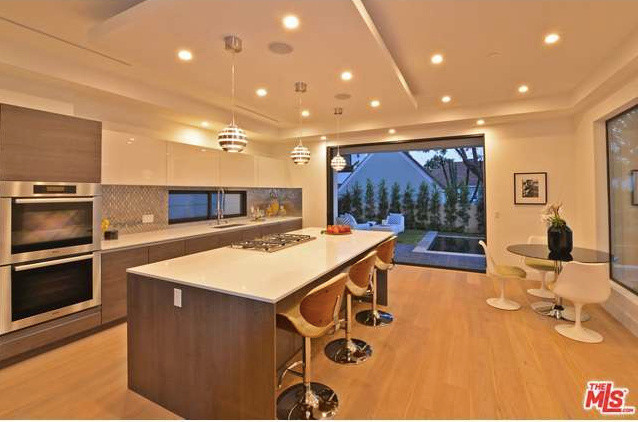 Inspiration for a large modern l-shaped separate kitchen in Los Angeles with an undermount sink, flat-panel cabinets, grey cabinets, quartz benchtops, metallic splashback, metal splashback, stainless steel appliances, light hardwood floors and with island.