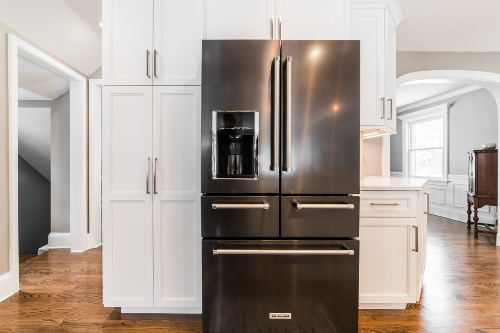 Inspiration for a mid-sized transitional l-shaped medium tone wood floor and brown floor eat-in kitchen remodel in Chicago with an undermount sink, recessed-panel cabinets, white cabinets, quartzite countertops, gray backsplash, subway tile backsplash, black appliances, no island and multicolored countertops