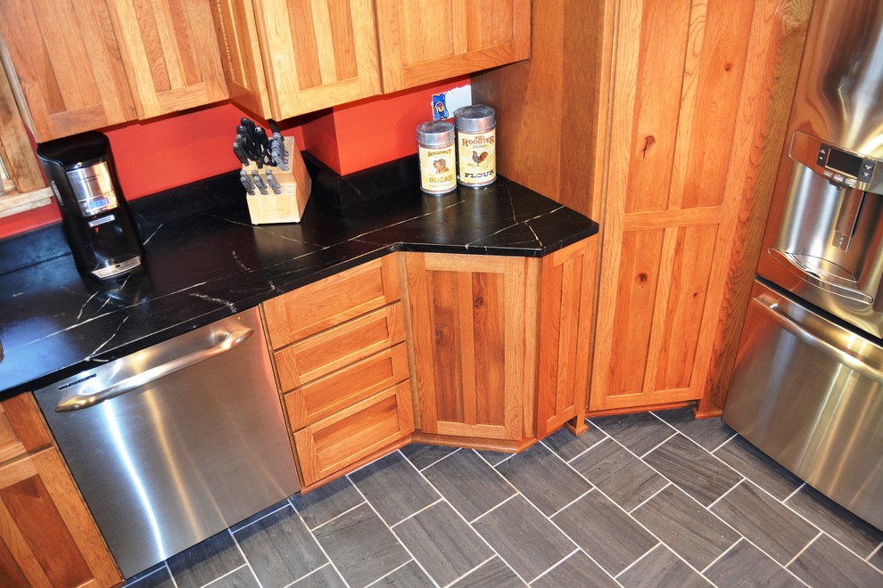 Inspiration for a mid-sized rustic l-shaped slate floor eat-in kitchen remodel in Burlington with an undermount sink, shaker cabinets, distressed cabinets, soapstone countertops, stainless steel appliances and a peninsula