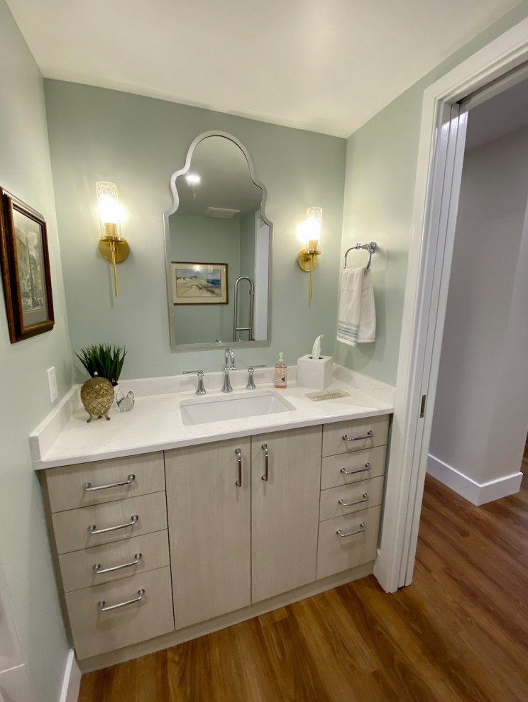 Photo of a mid-sized transitional bathroom in Philadelphia with flat-panel cabinets, light wood cabinets, an alcove tub, a shower/bathtub combo, a two-piece toilet, green walls, vinyl floors, an undermount sink, quartzite benchtops, brown floor, a shower curtain, white benchtops, a single vanity and a built-in vanity.