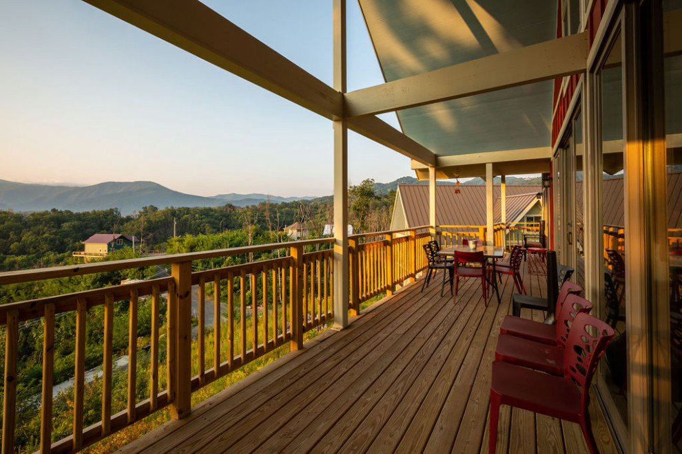 Example of a mid-sized mountain style backyard deck design with a roof extension