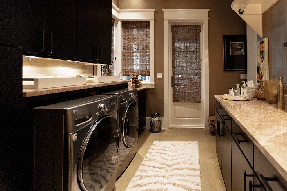 Mid-sized galley dedicated laundry room in Other with flat-panel cabinets, brown cabinets, granite benchtops, brown walls, concrete floors, a side-by-side washer and dryer and beige floor.